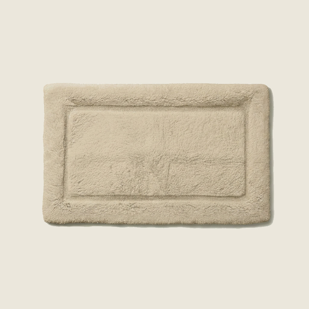Bath mat in soft ivory color photographed flat on plain background
