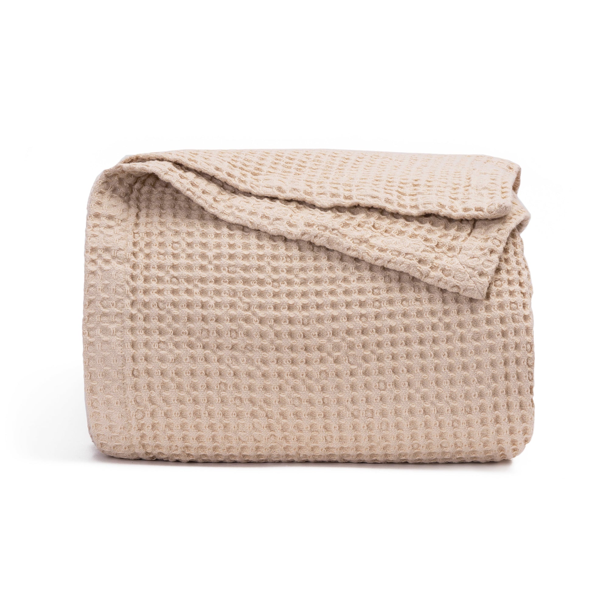Cream waffle weave cotton blanket folded neatly at the foot of a bed