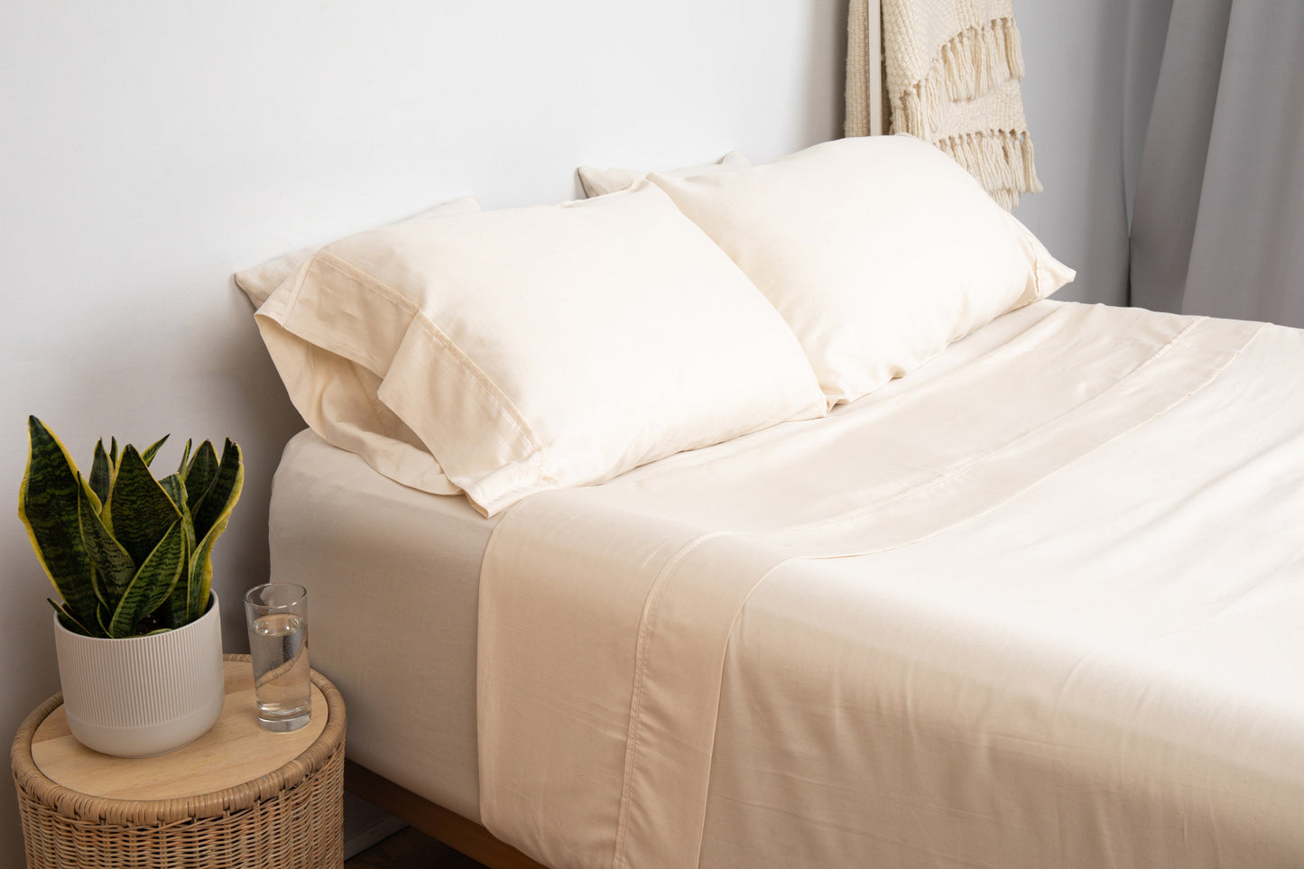 Organic sateen sheet set in blush pink shown styled on a wooden bench