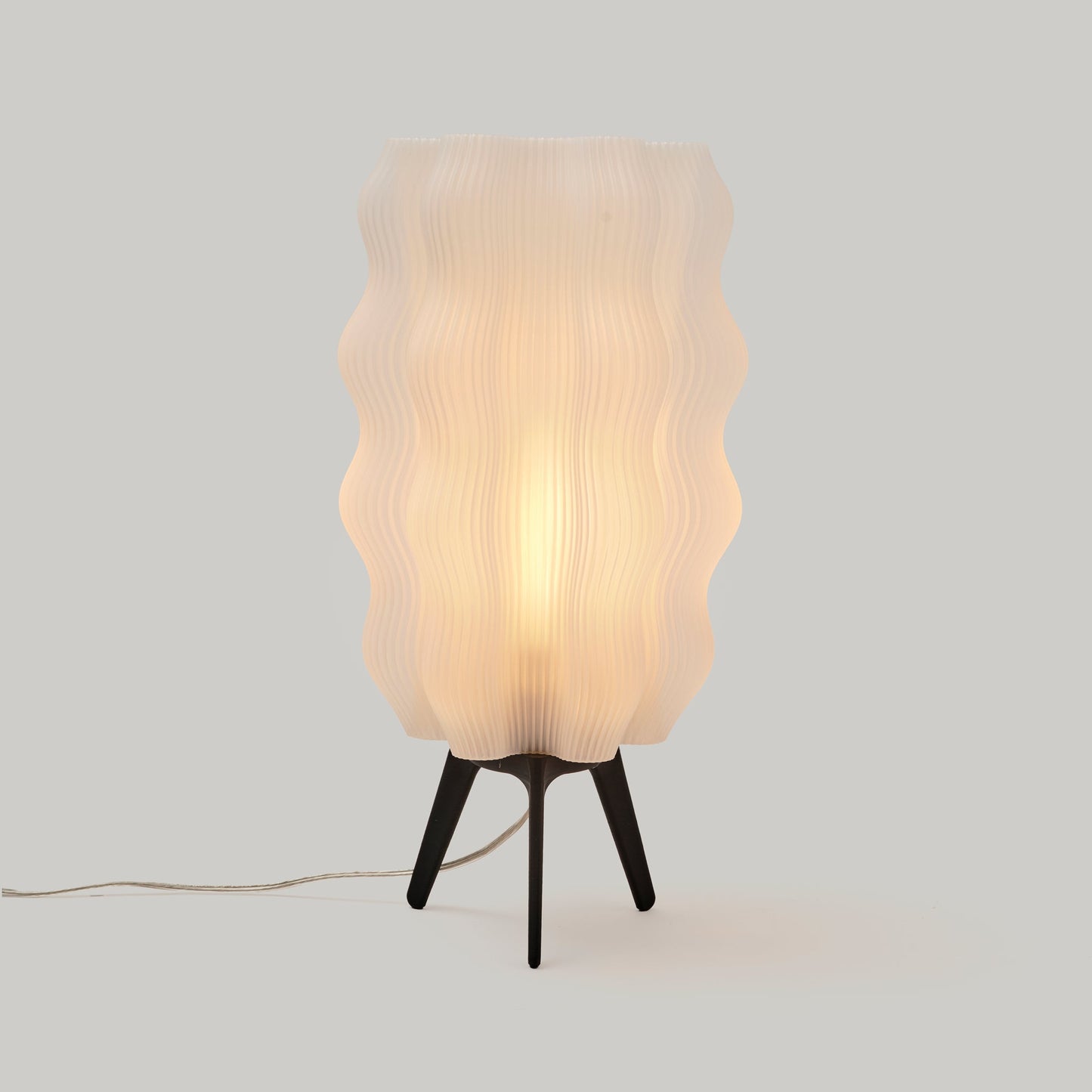 Tall matte black Wavy Lamp on plain studio background showing height