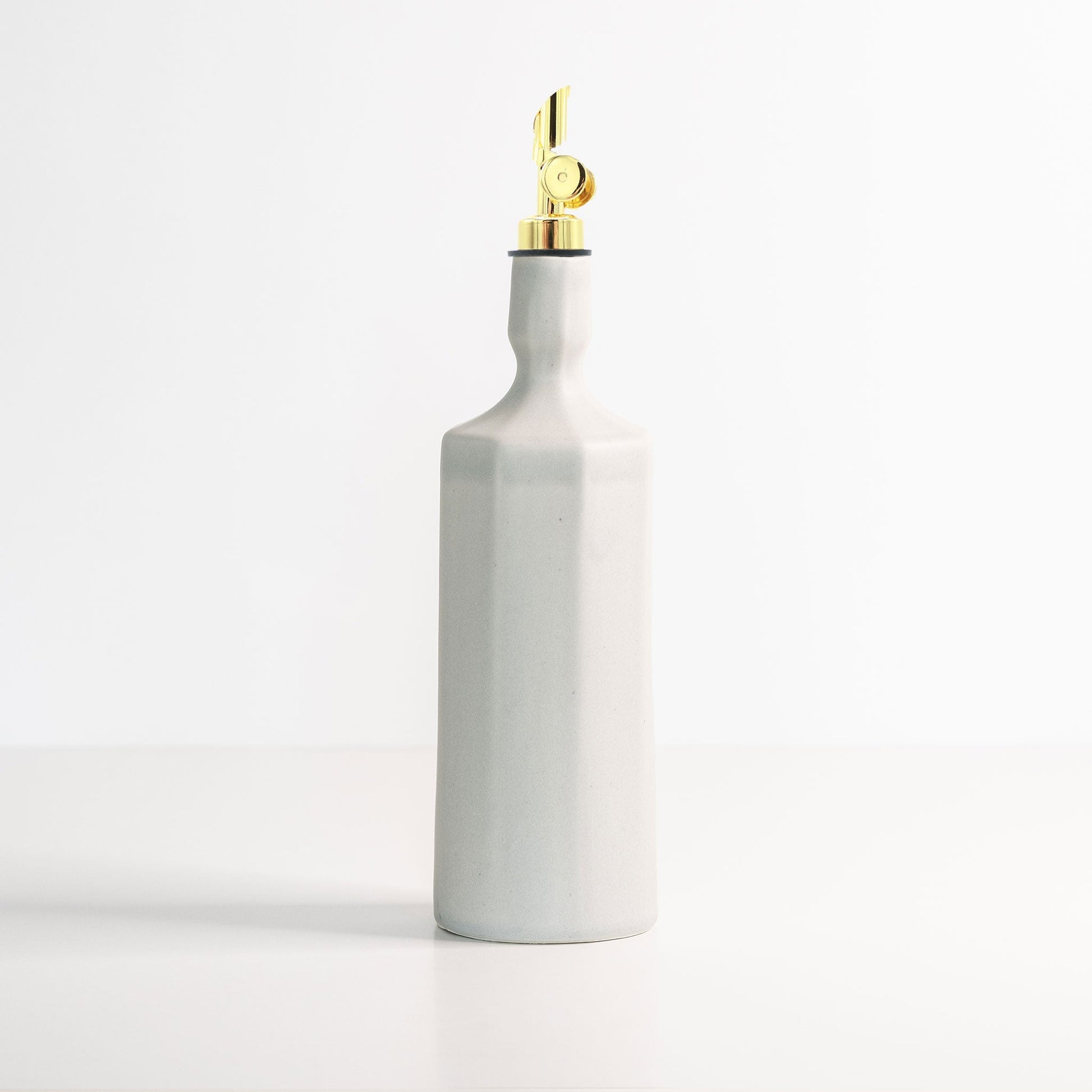 Elixir oil dispenser in white photographed in soft warm window light